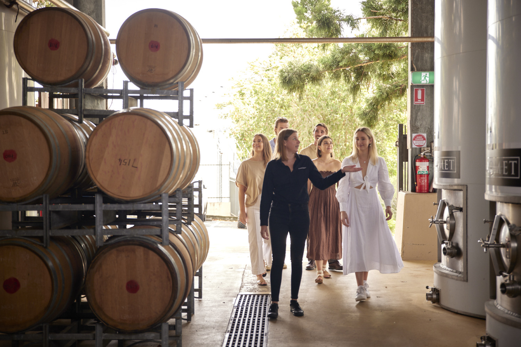 Woman giving tour of winery to a group of people 